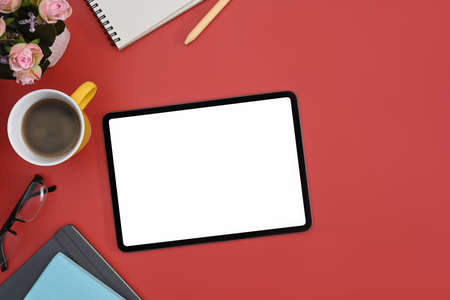 Mockup digital tablet, coffee cup and notebook on red background. Blank display for graphic display...