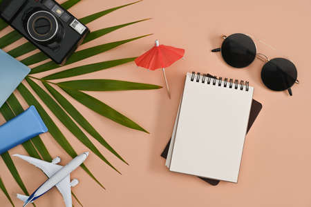 Flat lay laptop computer, retro camera, sunglasses and sunscreen bottles on beige background. Summer vacation concept.の写真素材