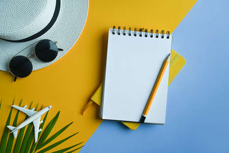 Notebook, hat, sunglasses and tropical palm leaves on colorful background. Travel, summer and holiday concept.の写真素材