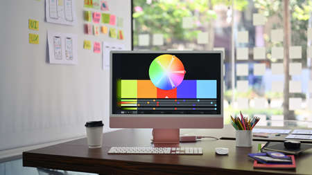 Designer working desk with modern computer, stationery and wireframe sketches of screens for mobile application on white board.の写真素材