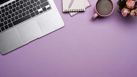 Laptop computer, notepad, and coffee cup on purple background. Flat lay, Top view.の写真素材