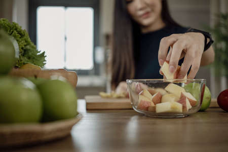 Young woman making fresh vegetarian salad in kitchen.  Healthy and wellness concept.の写真素材