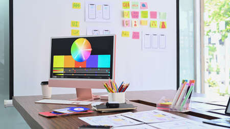 Creative designer workplace with digital tablet and wireframe sketches for mobile application on...