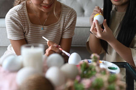 Mother and daughter spending time together before Easter festival and painting colorful Easter eggs.の写真素材