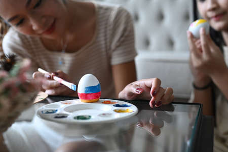 Mother and daughter spending time together before Easter festival and painting colorful Easter eggs.の写真素材