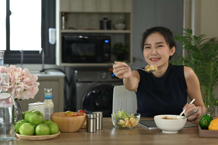 Young woman pouring sauce from bottle into healthy vegetable salad. Diet and Healthy food concept.