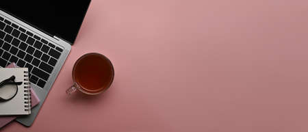 Coffee cup, laptop computer and notebook on pink background with copy space.の写真素材