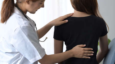Physiotherapist examining female patient with back injuries in clinic. Physical therapy concept.の写真素材