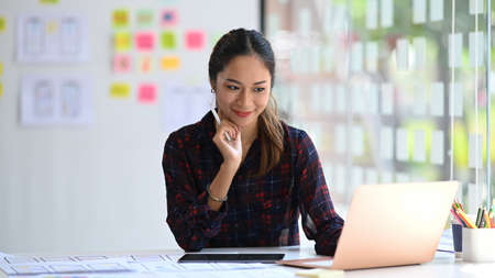 Attractive female web designer is working on application development for mobile phone at modern office.の写真素材