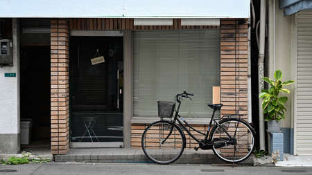 A bicycle with a wicker basket parked on city street in front of brick wall exterior facade of classic cafe.の写真素材