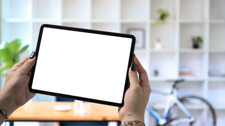 Stylish woman hand holding digital tablet and stylus pen with blurred office background.の写真素材