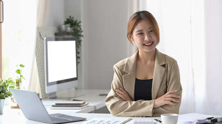 View over shoulder young businesswoman using laptop computer at her office desk.の写真素材