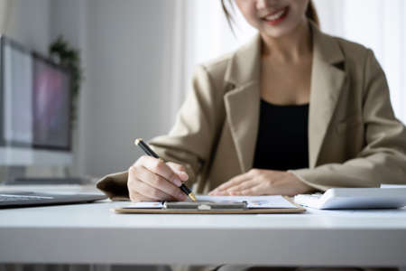 Cropped shot smiling female finance manager planning work projects at office desk.