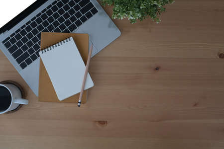 Simple workplace with computer laptop, notebook, potted plant and coffee cup. Flat lay.