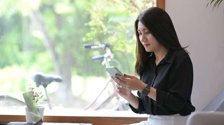 Young woman manager having business conversation via smartphone while sitting in cafe.の写真素材