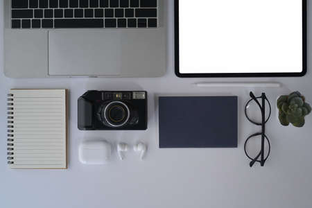 Flat lay designer workplace with digital tablet, camera, laptop, notebook and glasses.の写真素材