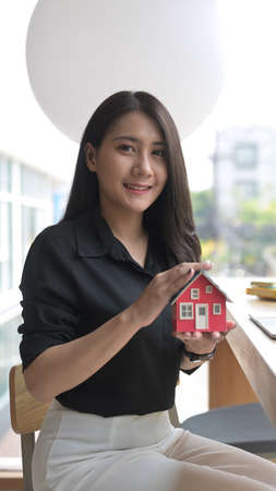 Attractive young woman hands holding house model. Real estate insurance and banking concept.の写真素材