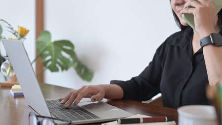 Back view of young businesswoman sitting in coffee shop and working online with computer laptop.