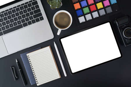 Above view digital tablet, laptop computer, notebook and color swatches on dark background. Creative...