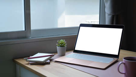 Feminine workplace with laptop computer, coffee cup and supplies on wooden table.