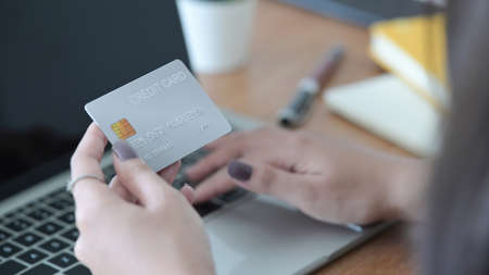 Close up view woman hand holding plastic credit card and using laptop. Online shopping, internet...