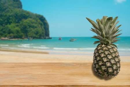 Ripe pineapple on woman hand with tropical beach in background. Tropical summer concept.の写真素材