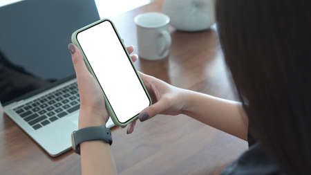 Close up view young woman sitting on yoga mat in living room and using smart phone.