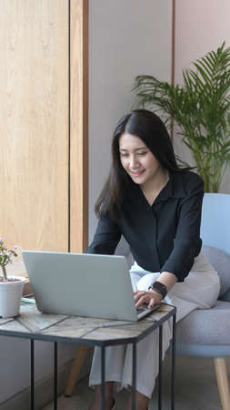 Relaxed asian woman enjoying her weekend, surfing internet on laptop at home.