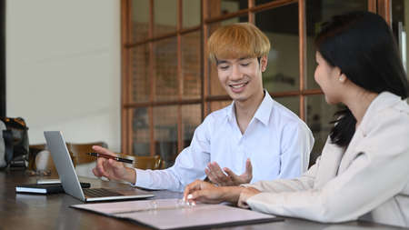 Shot of two young businesspeople sitting in their office using laptop and working together.の写真素材