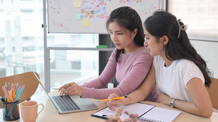 Two business colleagues brainstorming and discussing ideas of the new startup project together at creative office.の写真素材
