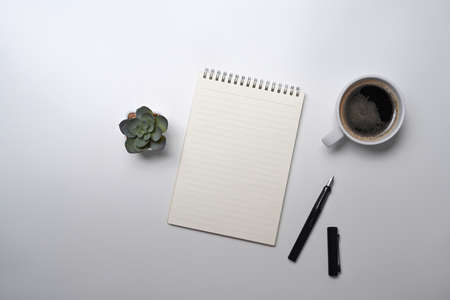 Top view notepad, coffee cup and pen on white office desk.の写真素材