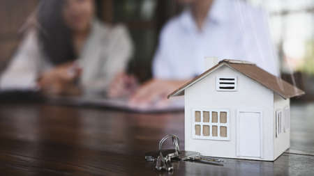 Close up view small house model and house keys on wooden table. New house, insurance and real estate...