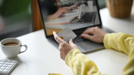Back view young woman holding credit card and using internet banking service on laptop computer.の写真素材