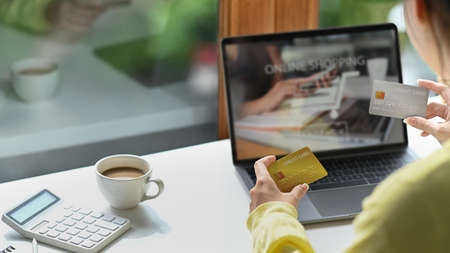 Back view young woman holding credit card and using internet banking service on laptop computer.の写真素材