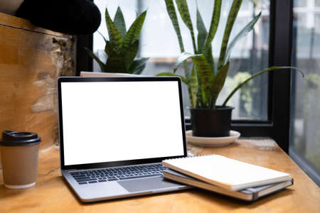 Comfortable workplace with laptop, notebook, coffee cup and house plat on wooden table.の写真素材