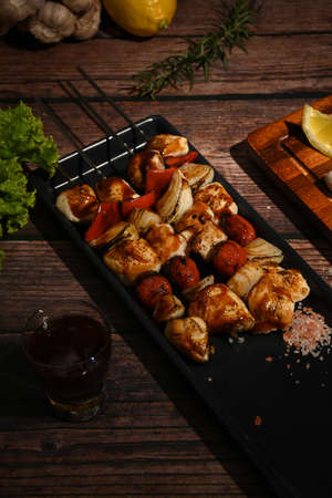 Close up of grilled vegetables and meat on sticks on rustic wooden table. Barbecue, food, party...