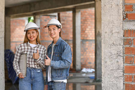 Two young engineers wearing safety helmet standing construction site. Industry, Engineer, construction concept.の写真素材