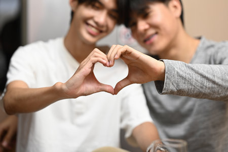Loving homosexual couple making heart with hands and smiling to camera. LGBT, relationships and equality concept.の写真素材