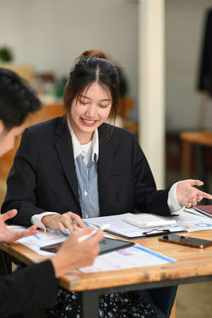 Cheerful young businesswoman having business conversation for project strategy with her colleague in modern office.の写真素材