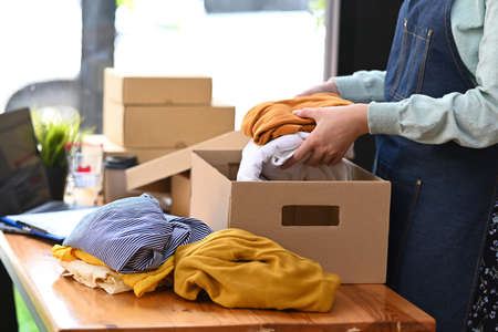 Cropped shot small business owner packing product in cardboard box for delivery to customers. Online selling, e-commerce.の写真素材