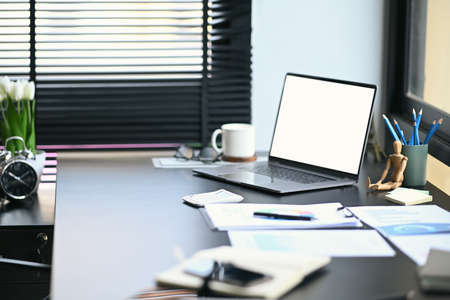 Modern office with computer laptop, stationery and financial documents.の写真素材