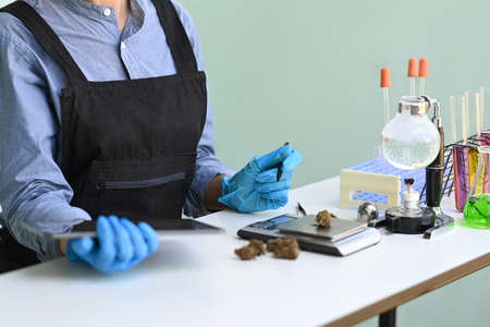 Cropped shot scientist researching and examining hemp oil in laboratory. Herbal alternative...