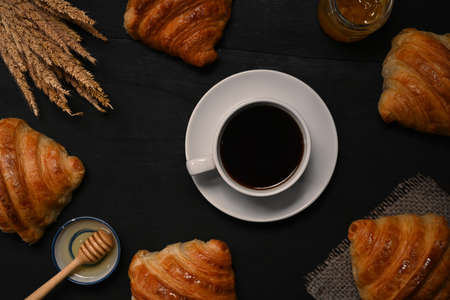 Coffee cup and freshly baked croissants on black wooden table. Top view.の写真素材