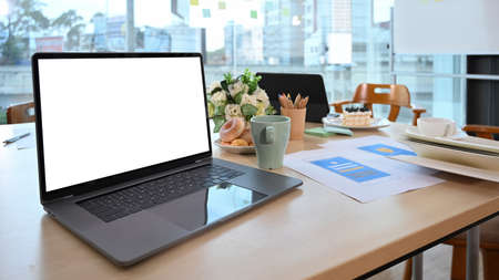Computer laptop, coffee cup and documents on office desk.