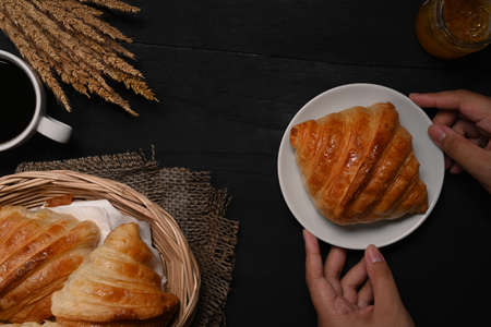 Above view woman holding plate with freshly baked homemade butter croissant.