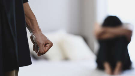 Aggressive man clenching fist in anger with crying woman in background. Concept of domestic family violence.の写真素材