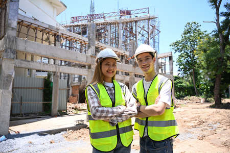 Architect, engineer in yellow vests and helmet standing at construction site.の写真素材