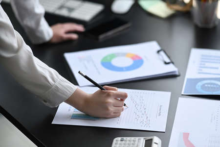 Cropped shot professional businesswoman checking and analyzing financial graph at her workplace.