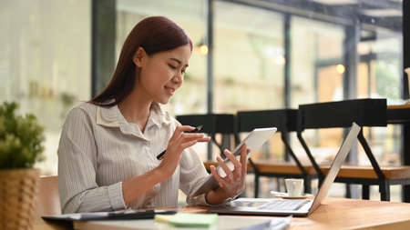 Smart asian female manager sitting in office and using modern devices. Technology, lifestyle...