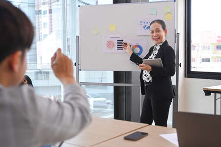 Confident business woman team leader standing near flip chart with graphs diagrams, presenting market research results at meeting.の写真素材